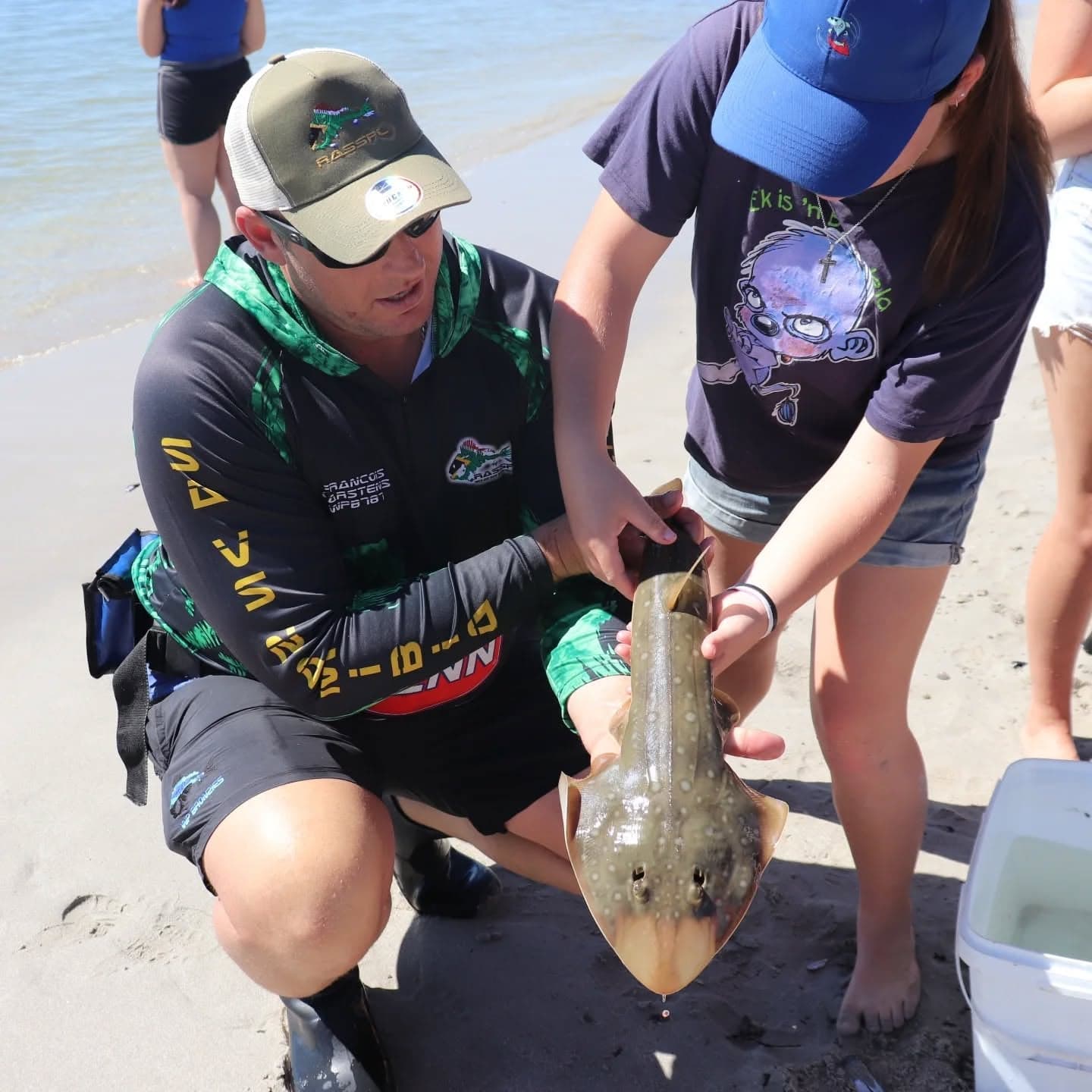 A WP Bronzies member and a young participant examining a fish together on the beach